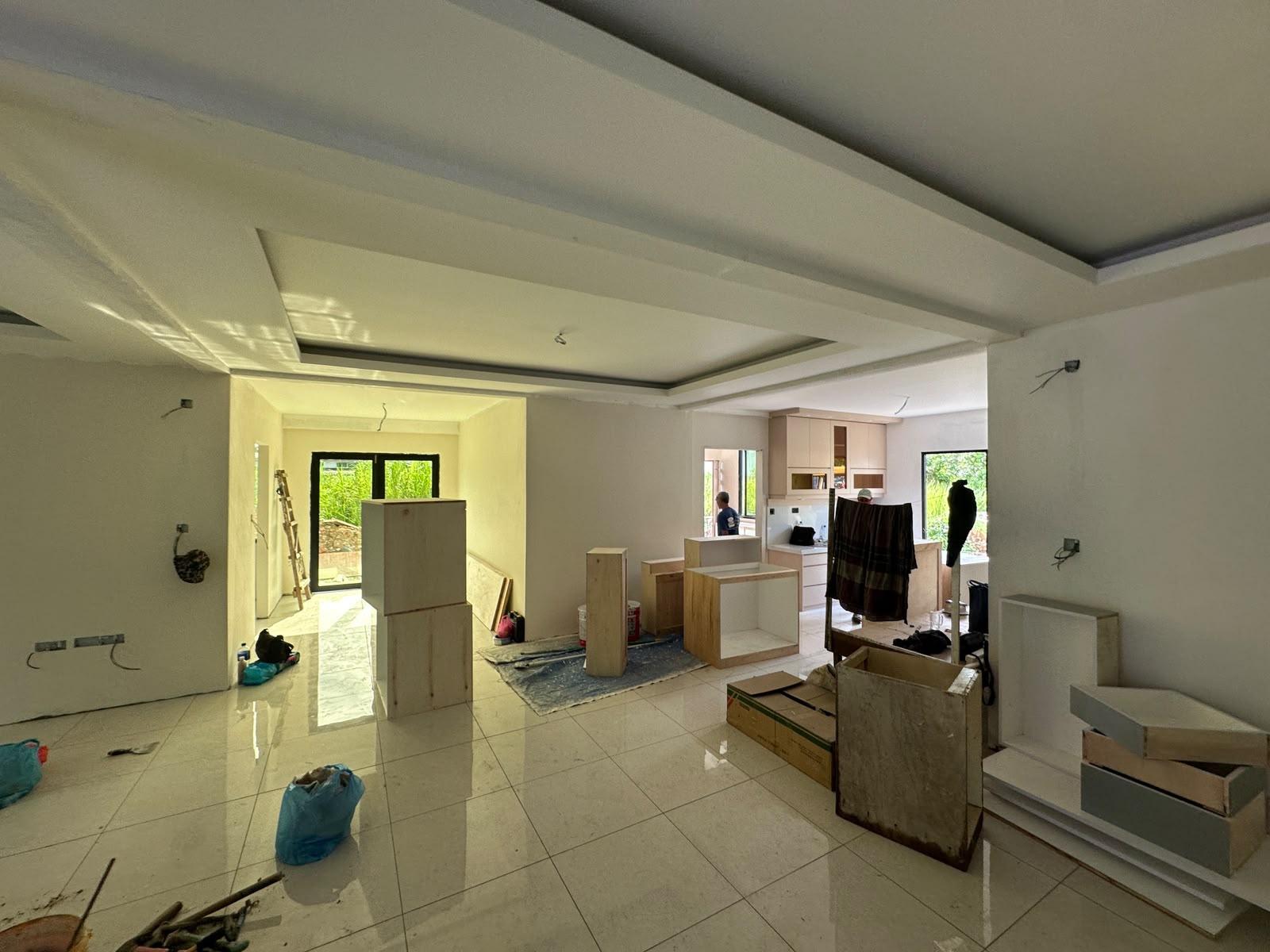 Open living area and kitchen with a ceiling feature and cabinets being installed