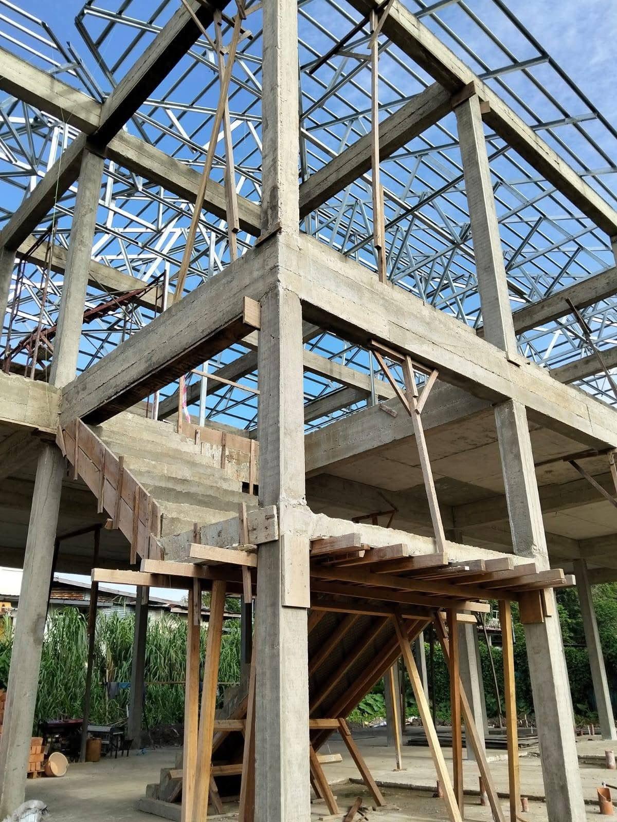 Concrete columns, beams and a staircase under steel roof trusses